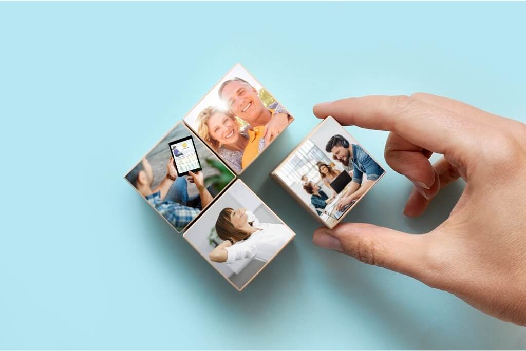 Eine Hand platziert einen Holzbaustein mit einem Bild in einer Anordnung von vier Bausteinen.